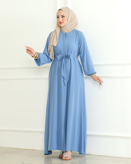 Blue modest maxi abaya with self-tie waist belt and ruffled cuffs, styled with a beige hijab – front angle view
