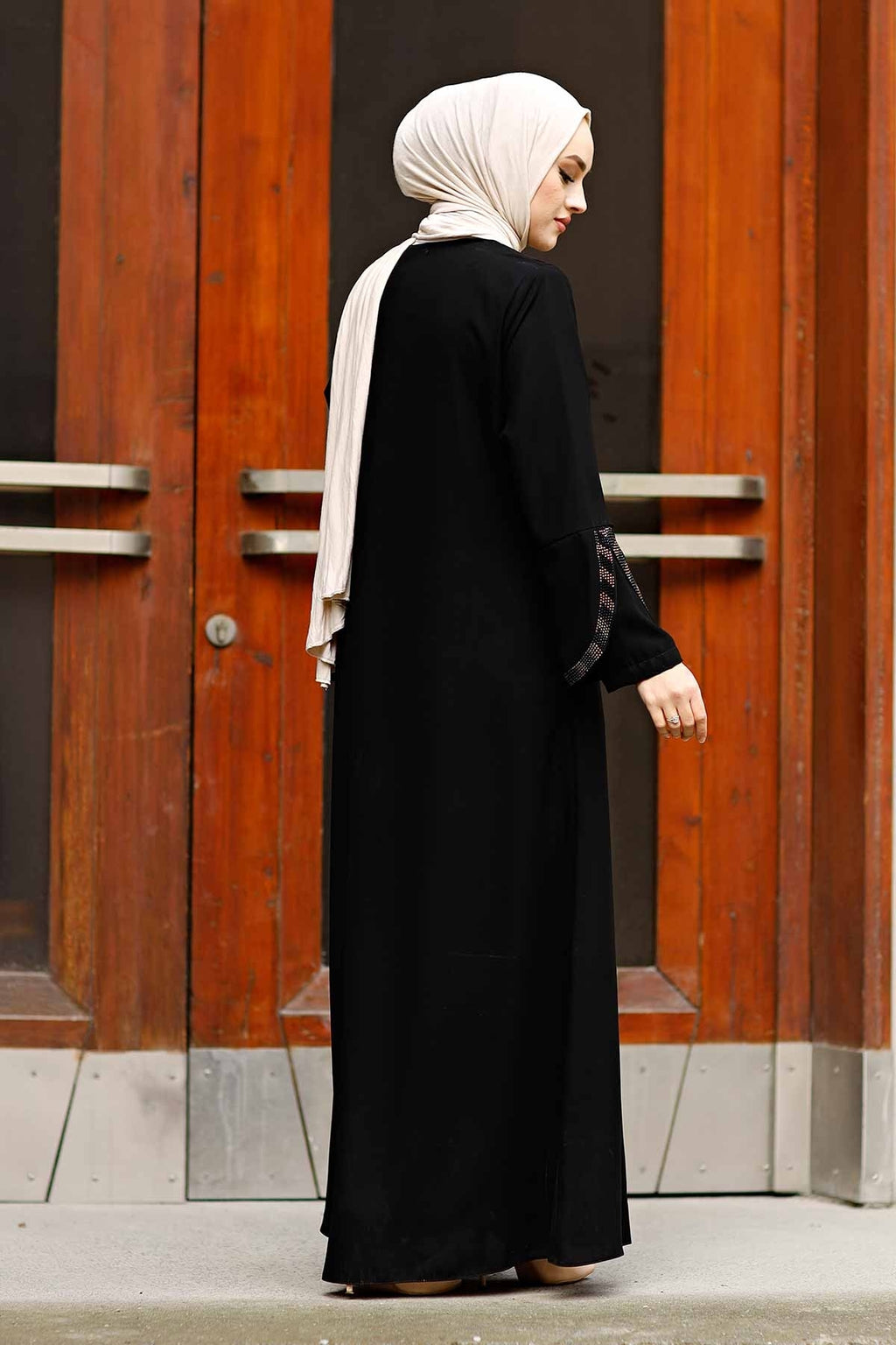 Full-length black rhinestone abaya layered over an outfit, floor-length hem