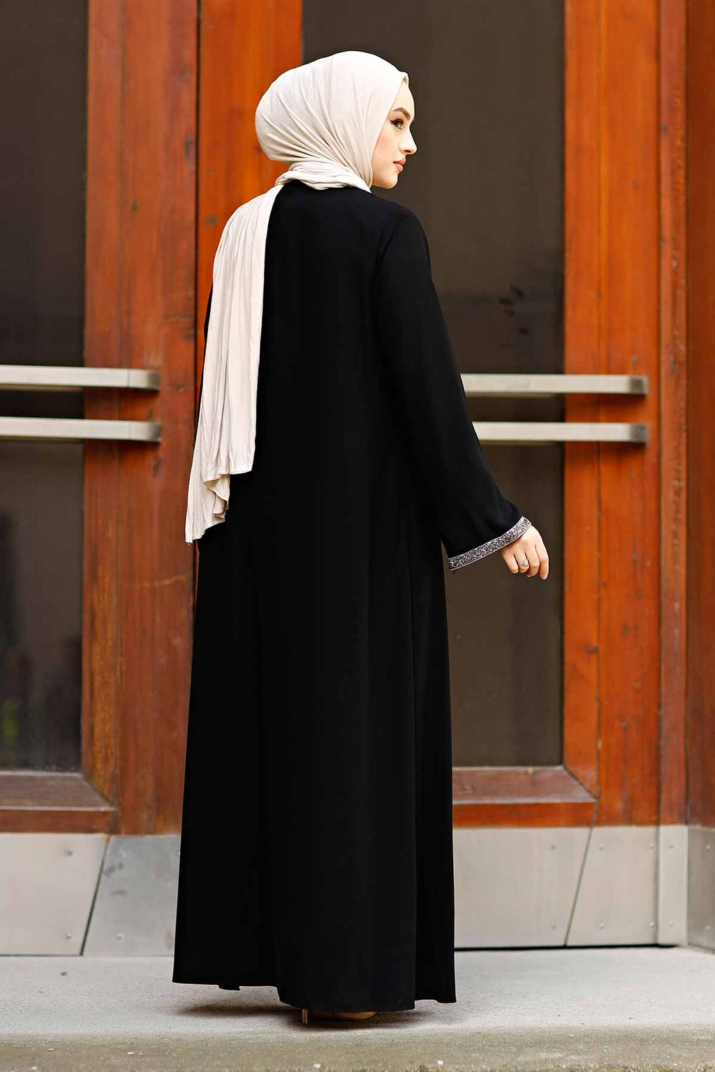 Detail of black abaya front zipper with decorative tassel pull and stone border