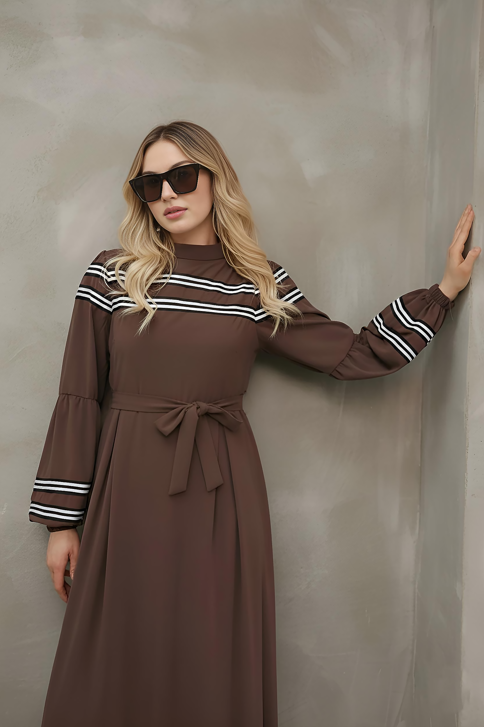 Side view of brown striped-trim maxi dress showing A-line skirt and front pleats
